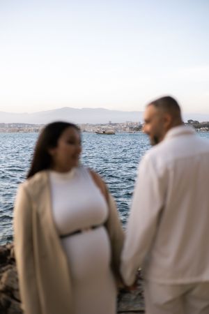 Couple in white clothing silhouetted against an ocean backdrop at sunset.
