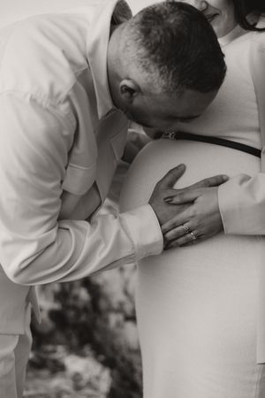 Intimate black and white photographs showing gentle moments with a pregnant belly.