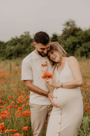 A couple sharing an intimate moment in a field of orange poppies at sunset.