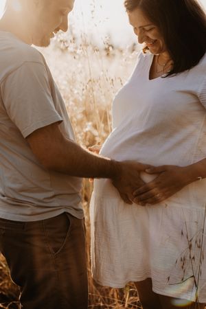 Tender maternity moments captured in soft golden light outdoors.