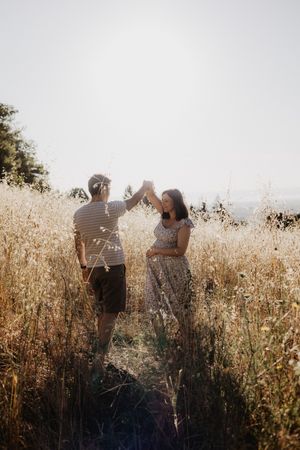 A couple shares intimate moments in a sun-drenched field of tall grass.