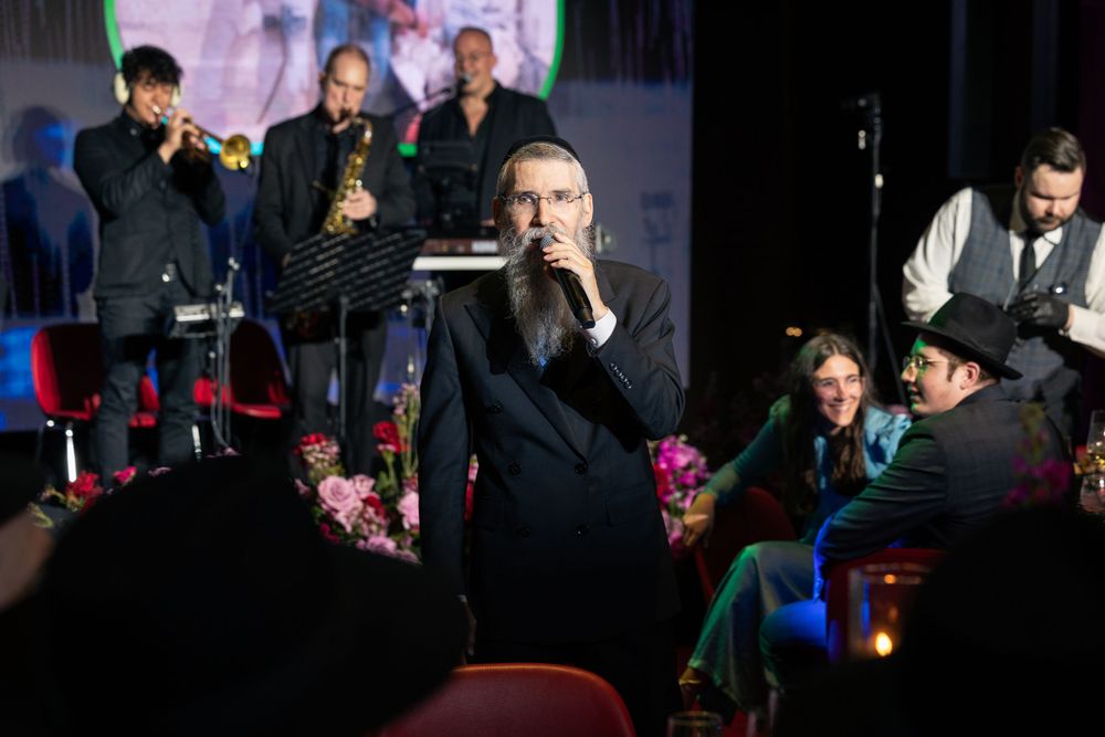 Dark auditorium setting with performers and audience members during an evening event.