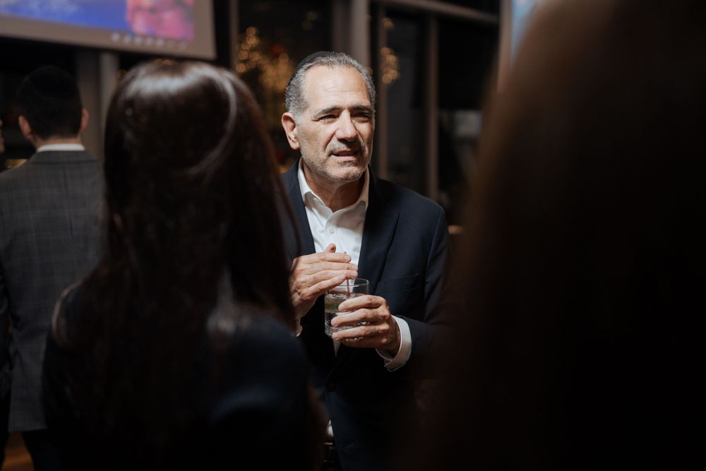 A person in formal attire engaging in conversation at an evening social event.