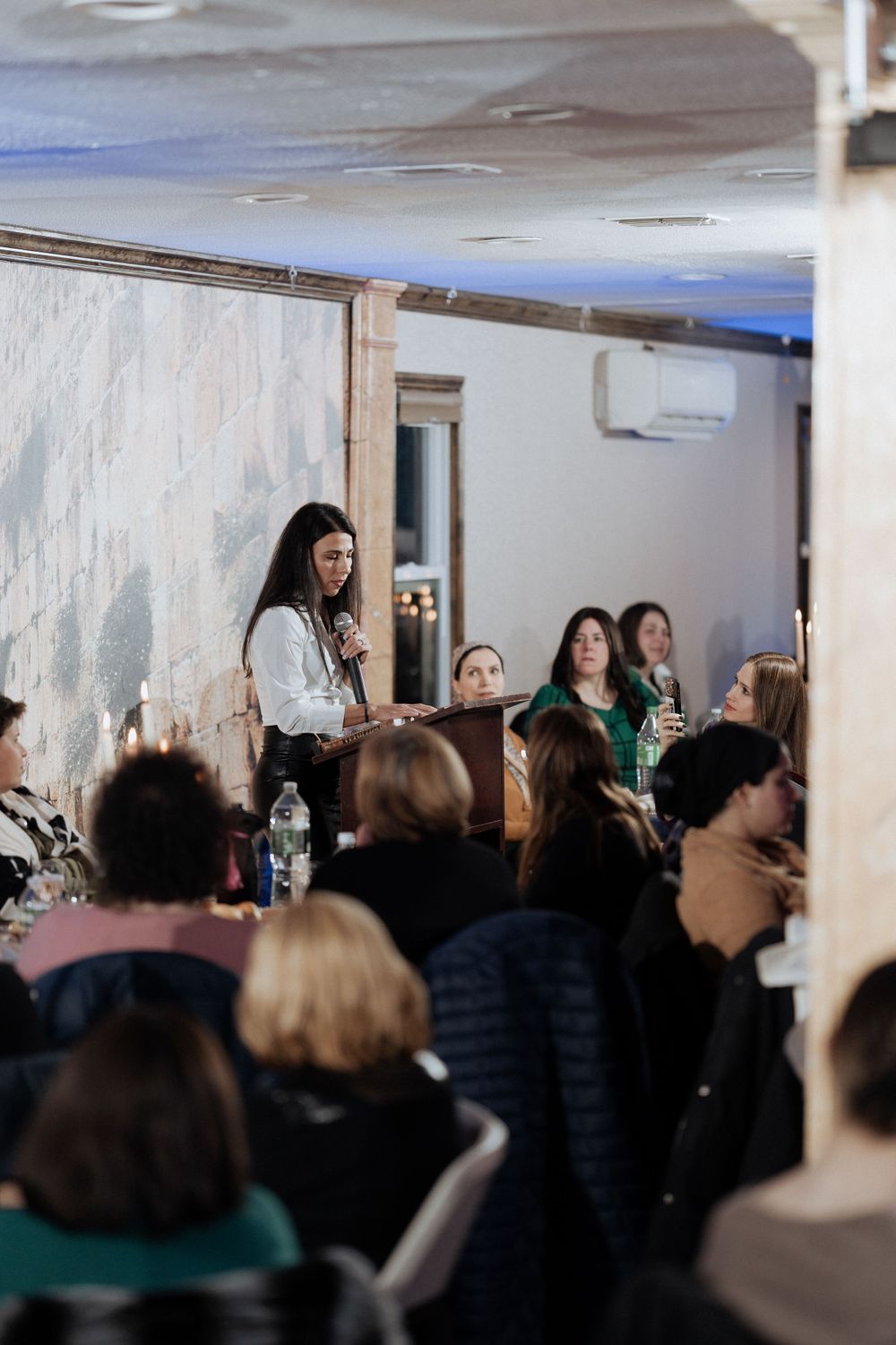 A speaker addresses a crowded indoor audience from a podium during an event.