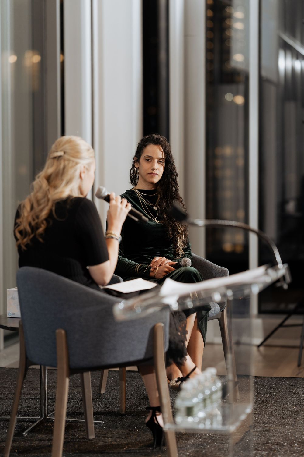 Two people engaged in a seated discussion at a professional event with a clear podium.