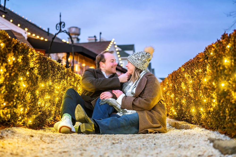Winter engagement photos with couple against backdrop of holiday lights.