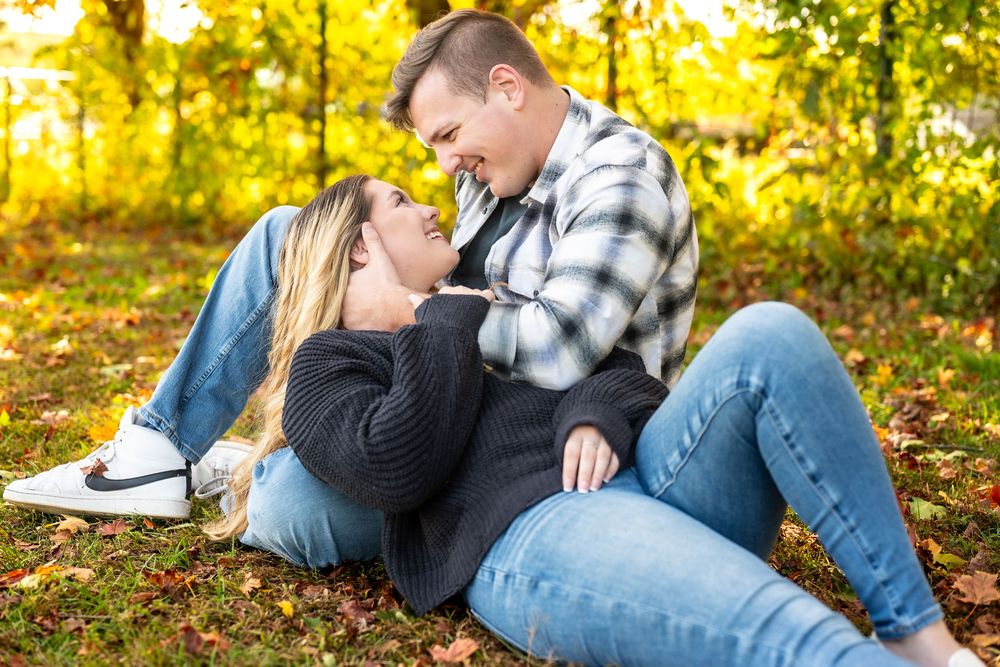 A romantic autumn moment captured on a blanket surrounded by fallen leaves.