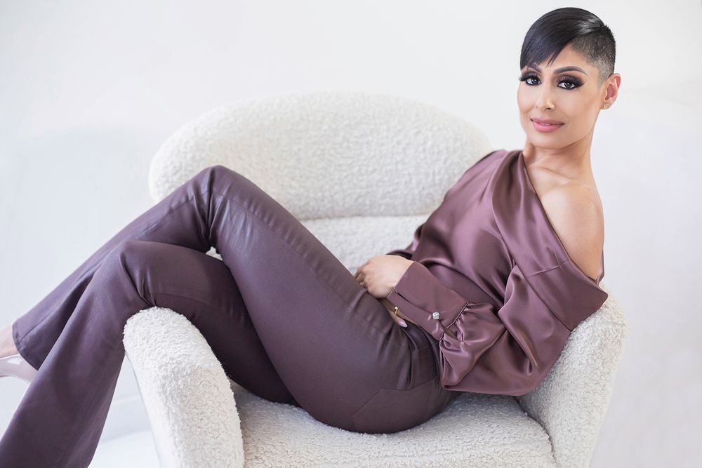 Model lounging on white chair wearing mauve satin outfit.