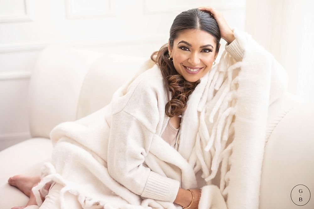 Cozy lifestyle portrait of person relaxing in white robe and blanket on comfortable chair.