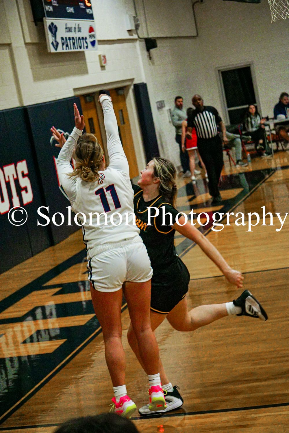 Female basketball player #11 shoots over defender during high school girls basketball game.
