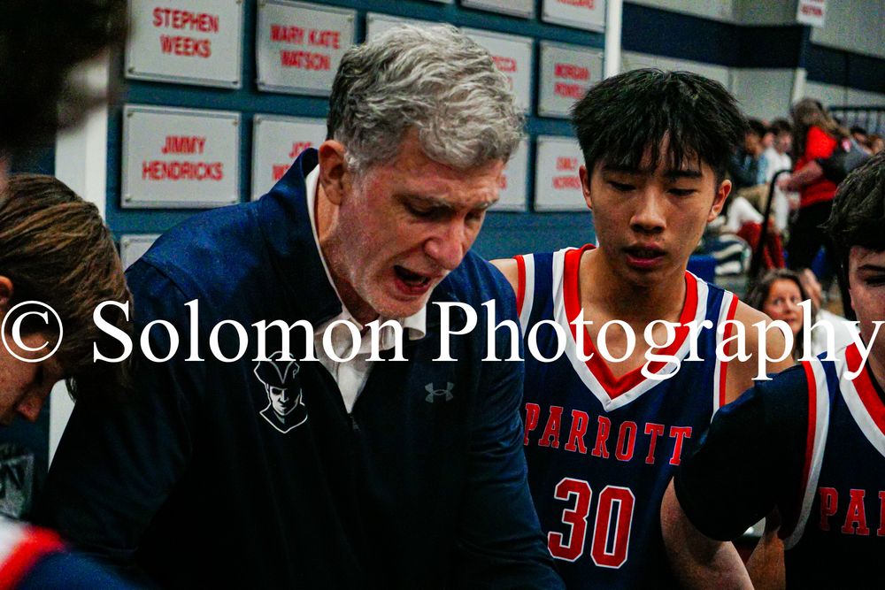 Basketball coach instructs player #30 during timeout at high school basketball game.