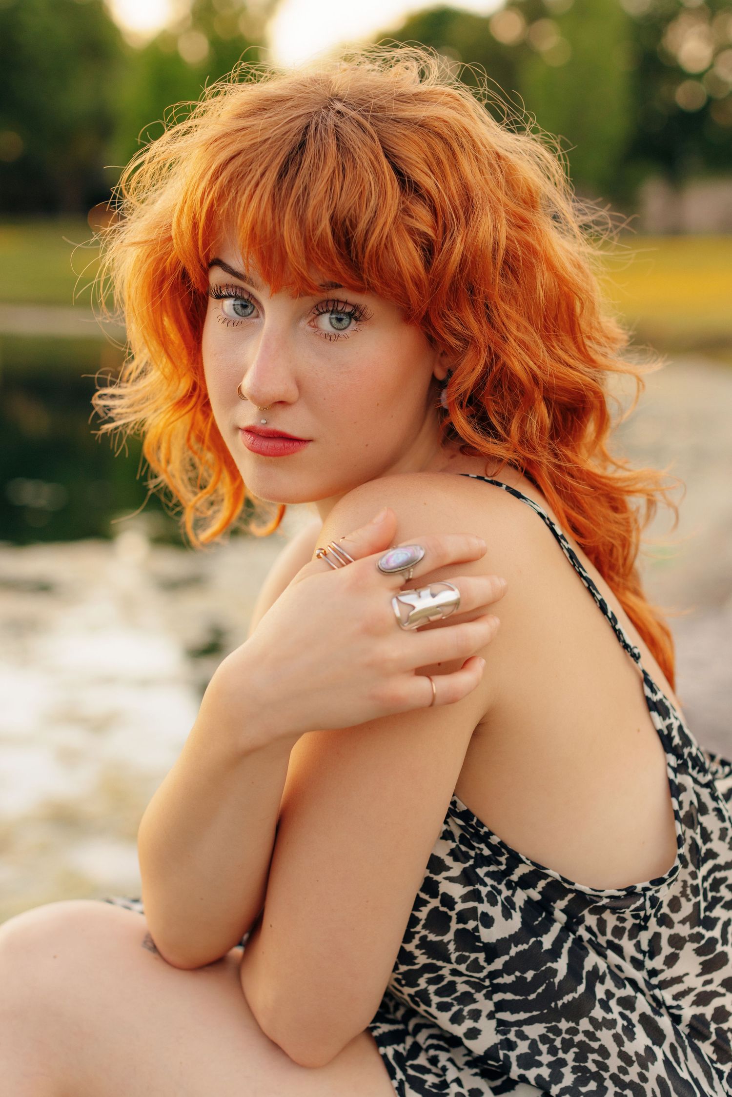A feminine figure poses outdoors wearing a leopard print dress at sunset.