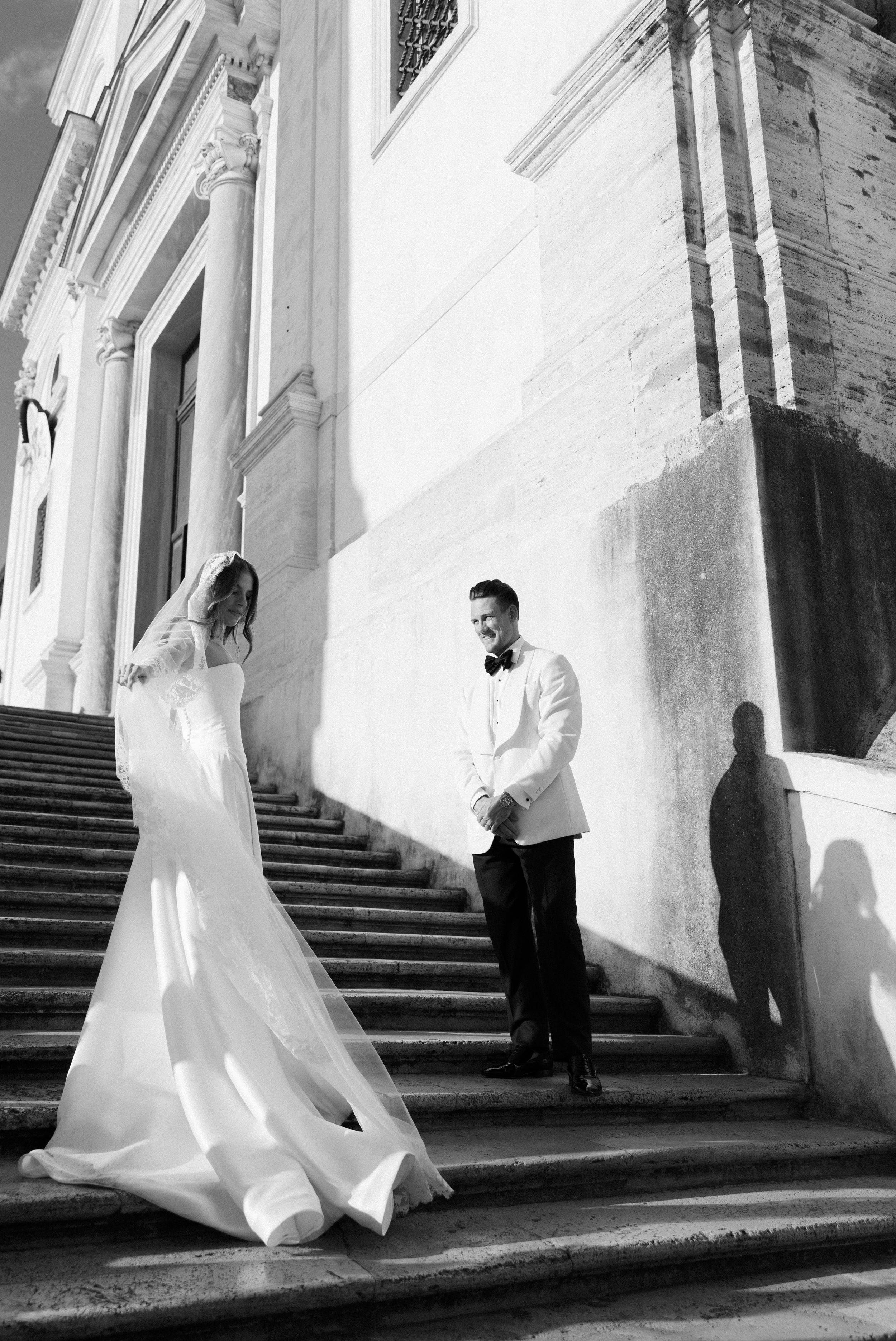 A series of black and white wedding photos showing a bride and groom walking up grand stone stairs in dramatic lighting.