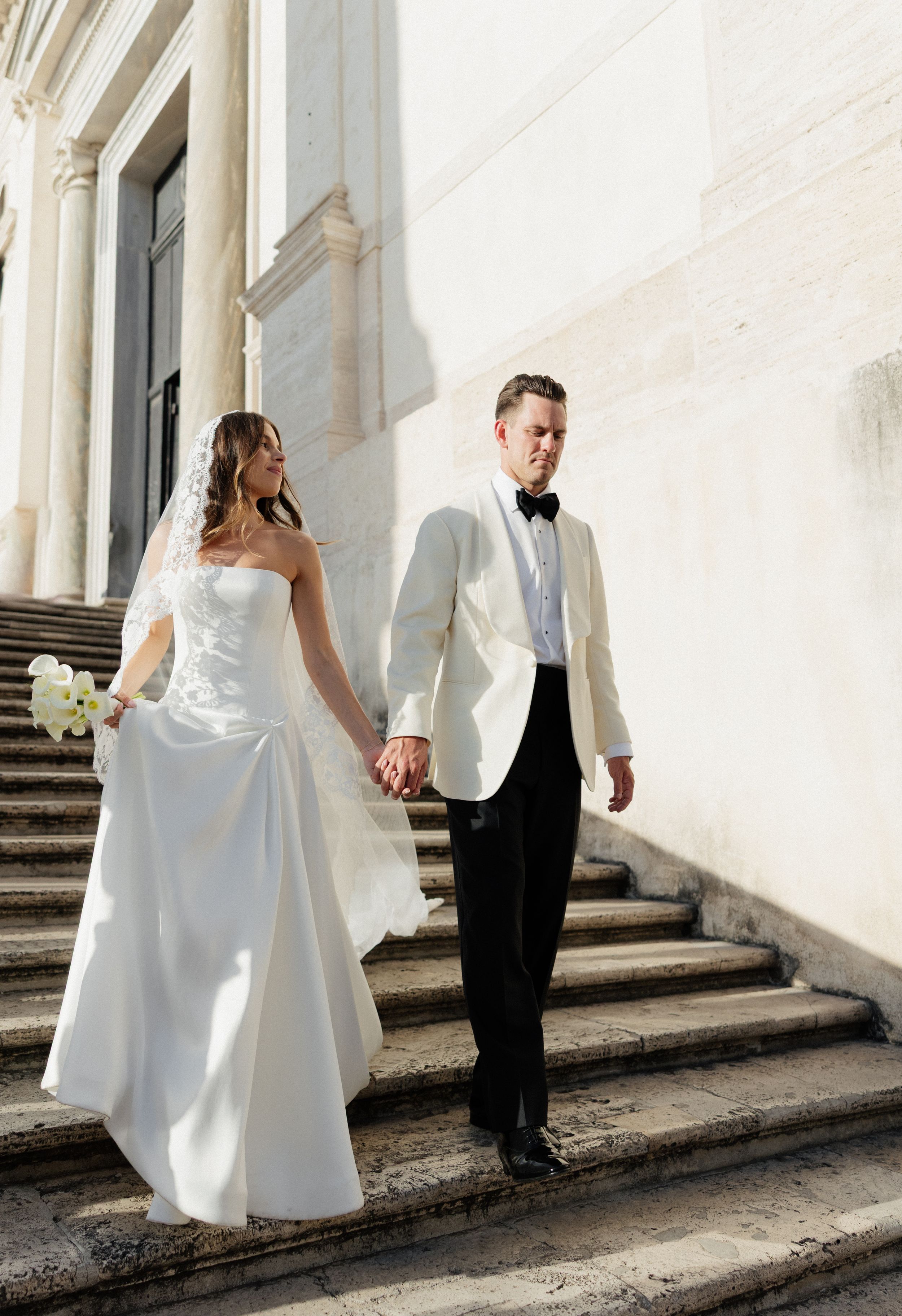 A bride and groom walk hand in hand down elegant white stone steps in a sequence of romantic wedding photos.