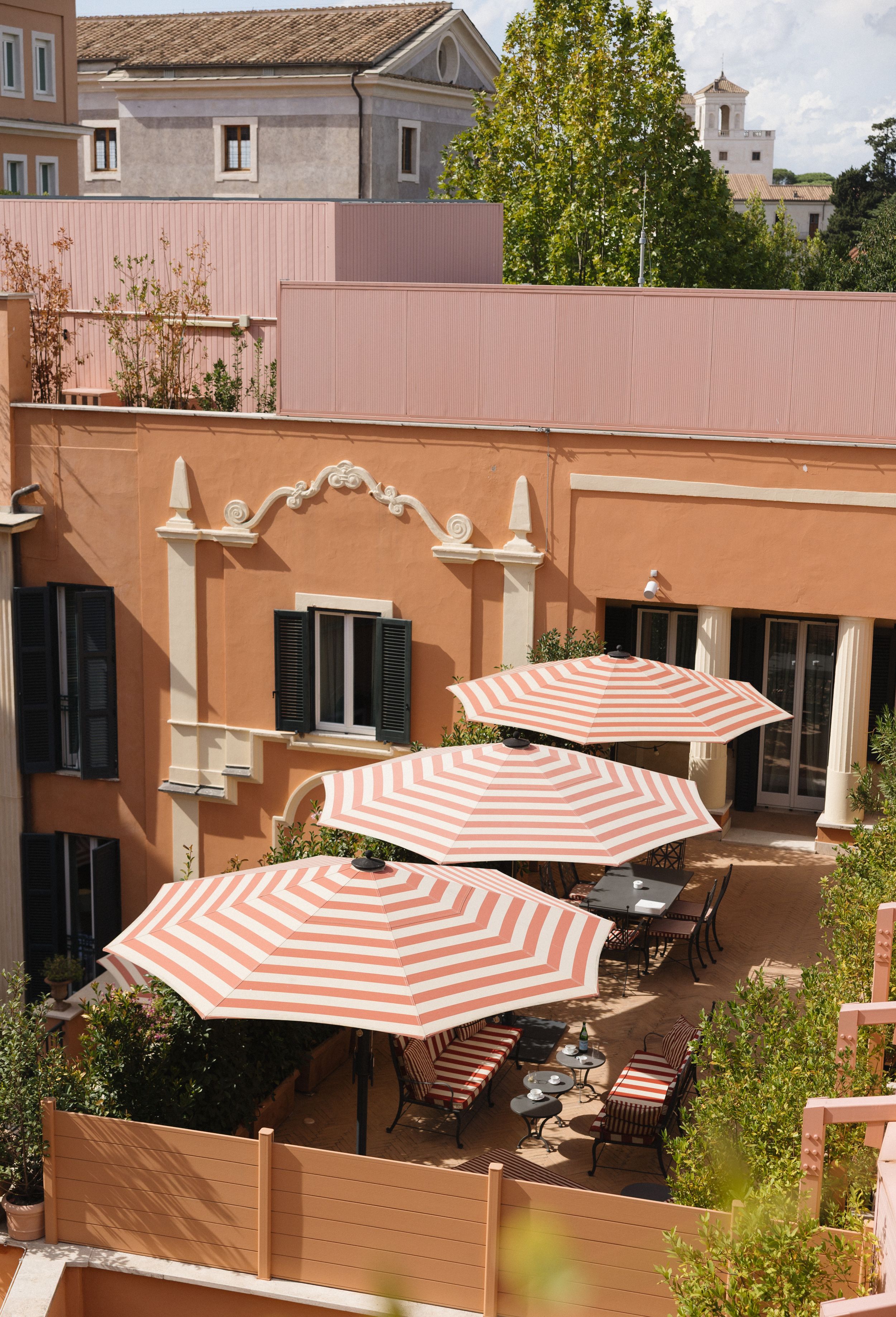 A rooftop terrace with orange-and-white striped umbrellas and wooden deck furniture creates a relaxing outdoor space.
