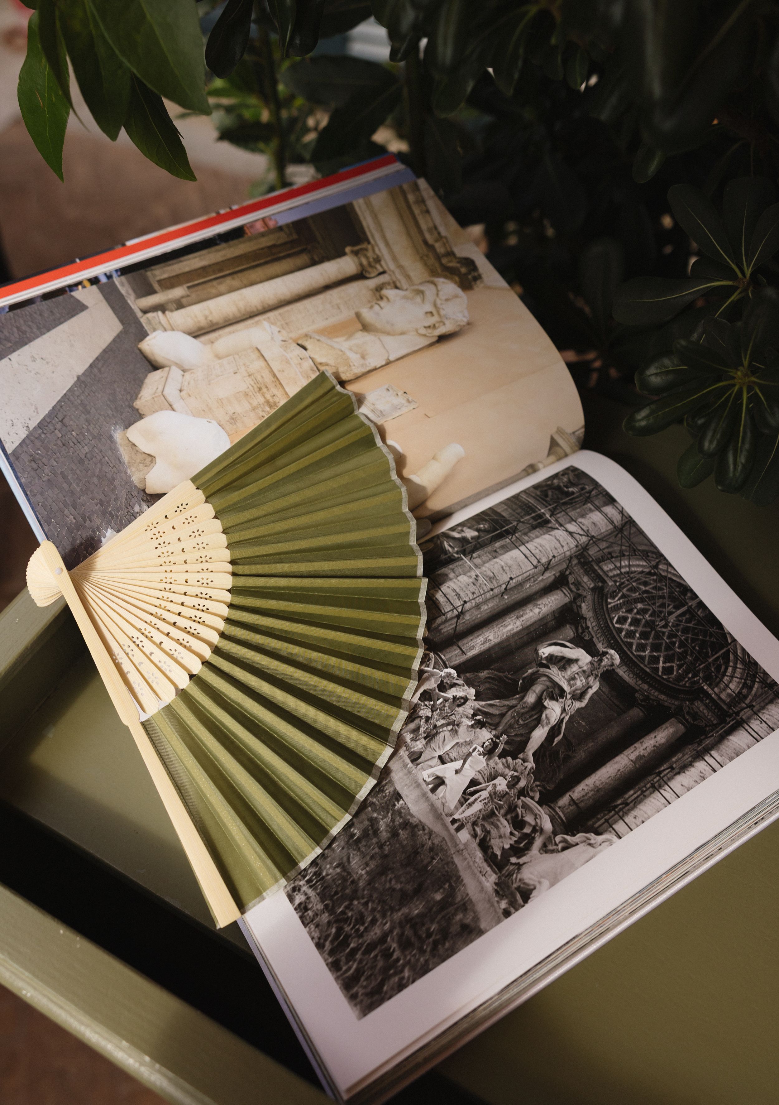 Decorative paper fans displayed on an open book with black and white vintage photographs.