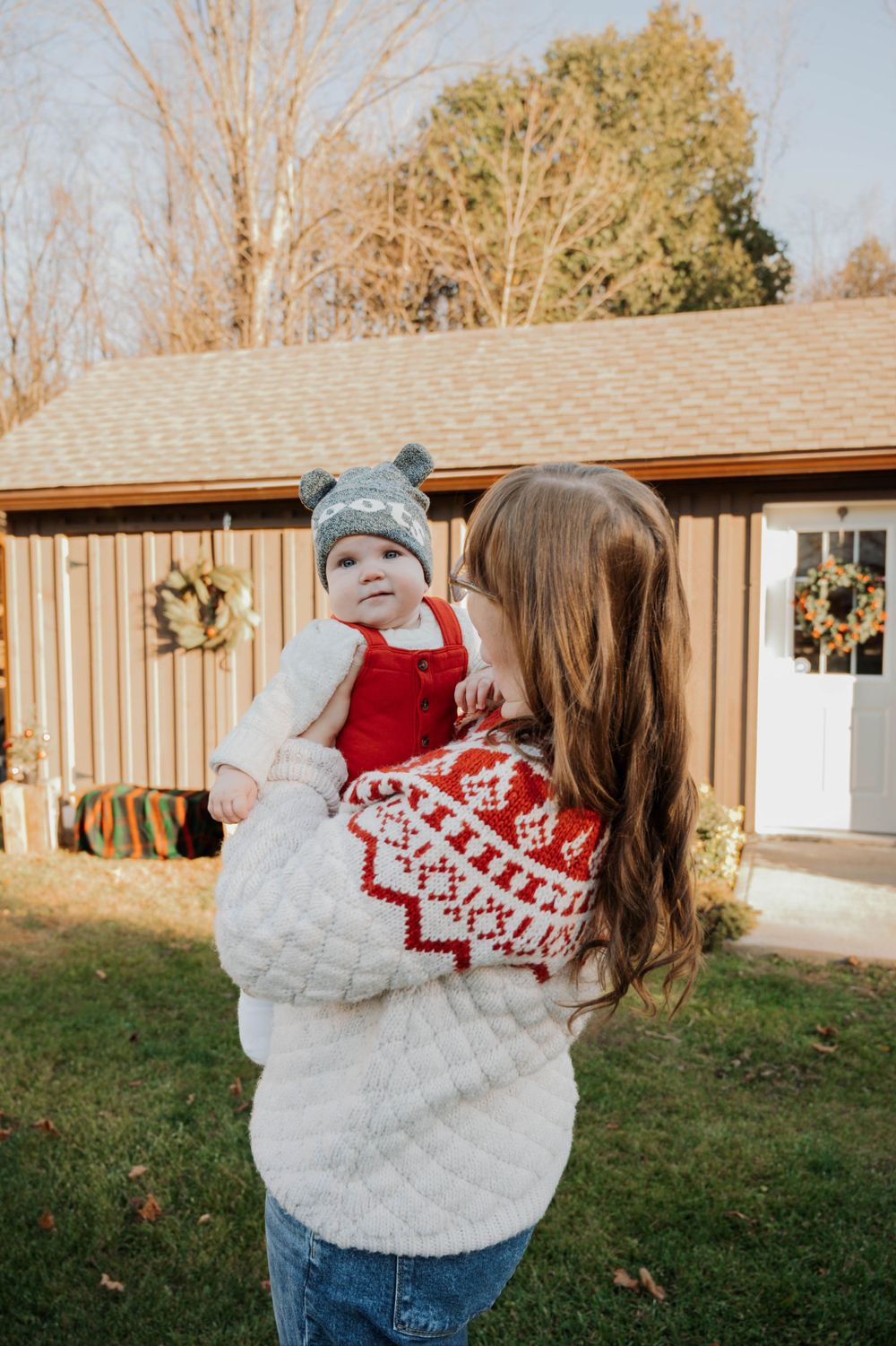 Winter holiday portrait outside wooden cabin with matching festive sweaters and knit hats.