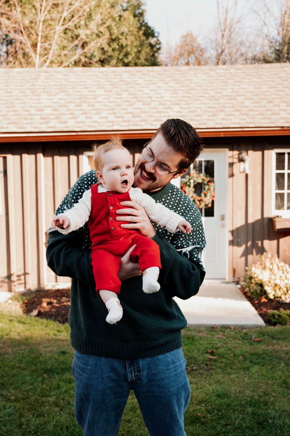 Joyful winter moment in matching holiday sweaters outside rustic cabin.