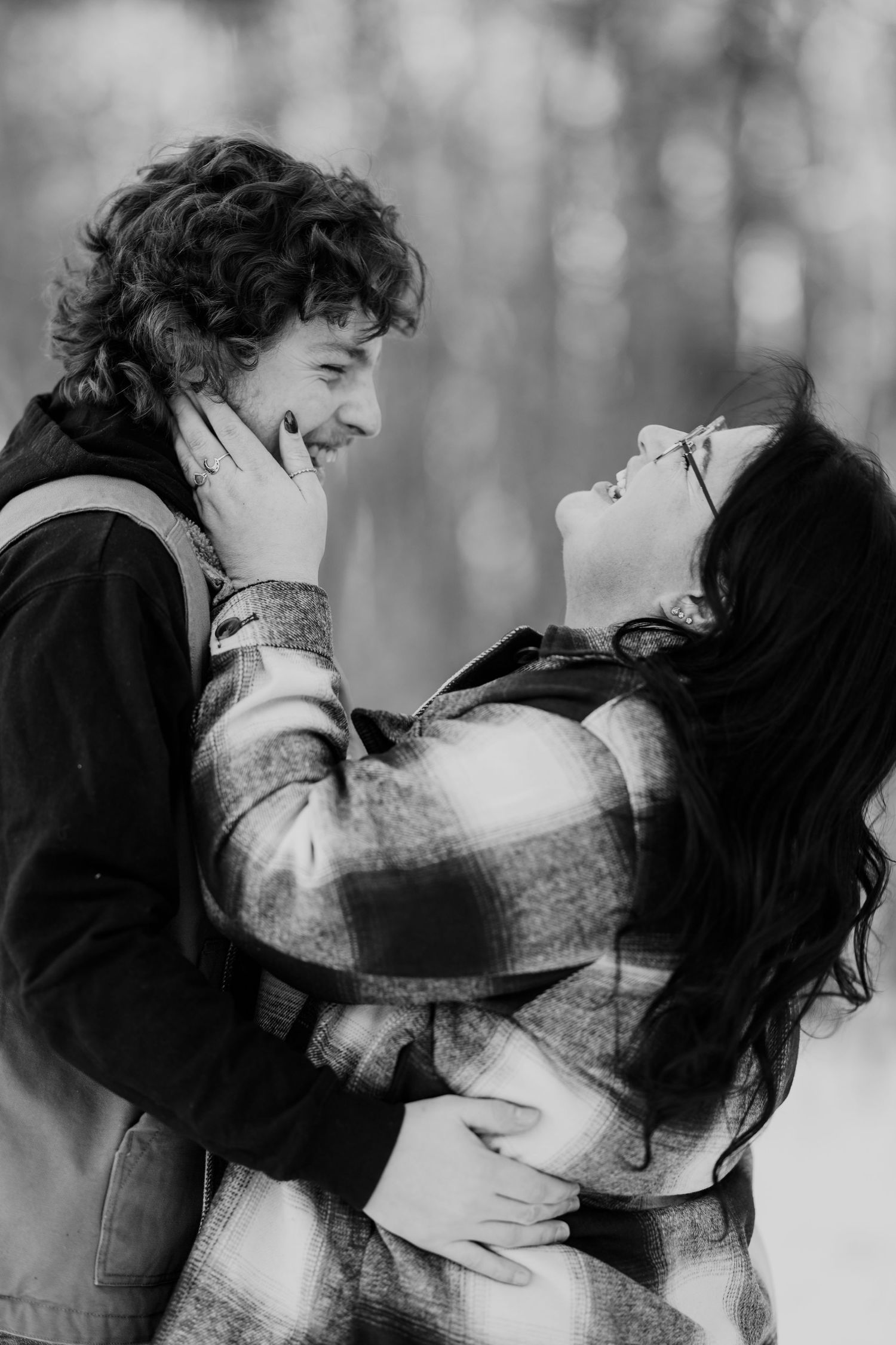 A black and white portrait of a couple in plaid sharing an intimate moment outdoors.