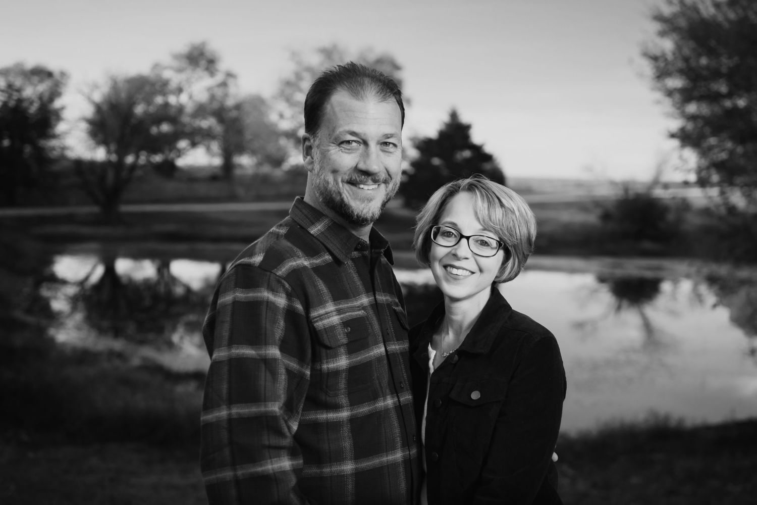 Black and white portrait of a couple standing by a lake at sunset.North Texas Family Photography