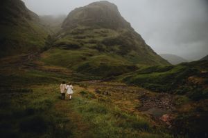 Misty mountain landscape in Scotland with hiking trail and green hills under cloudy skies.