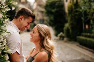 A romantic couple sharing a tender moment in a sunny garden setting with blooming flowers nearby.