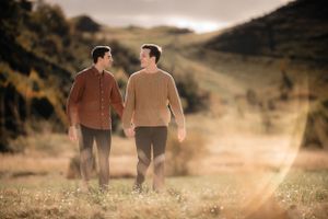 Two figures walking together along a rural path on a misty mountain hillside at sunset.