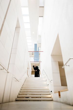 Figure in black silhouetted against bright white modern interior staircase with geometric architectural elements.