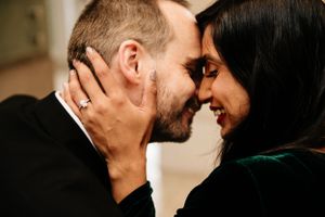 A couple touches foreheads intimately while smiling and sharing a tender moment together.
