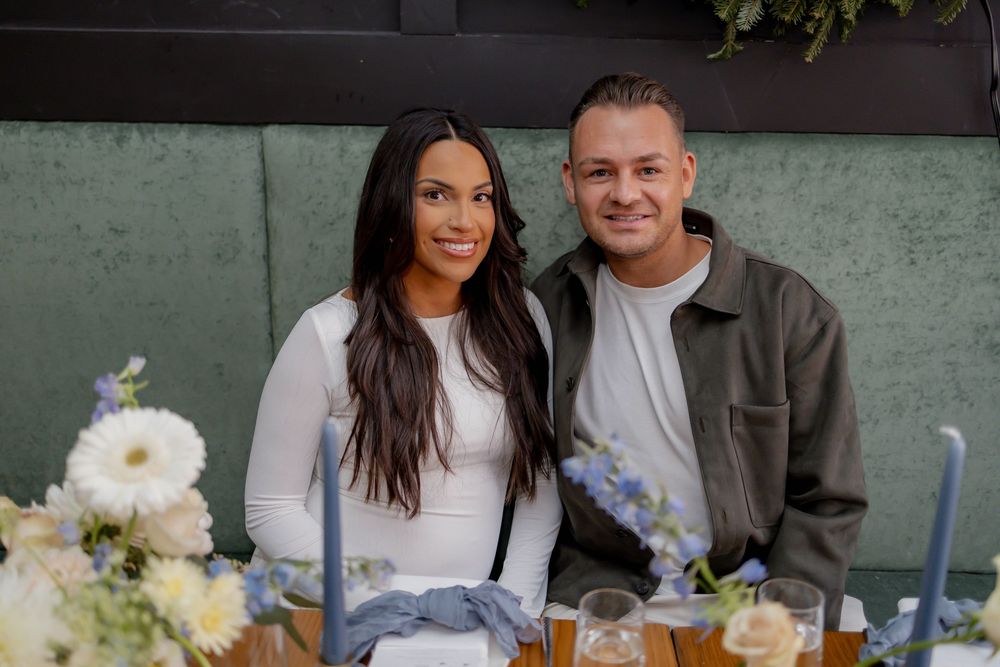 Couple smiling together at a decorated table with blue candles and white flowers at an elegant event.