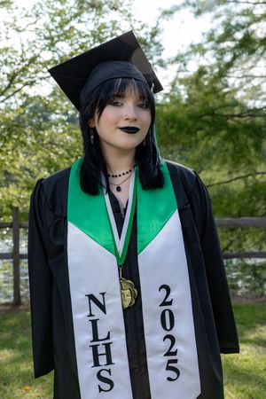 High school graduate in black cap and gown with NLHS 2025 stole and gold medal posing outdoors.