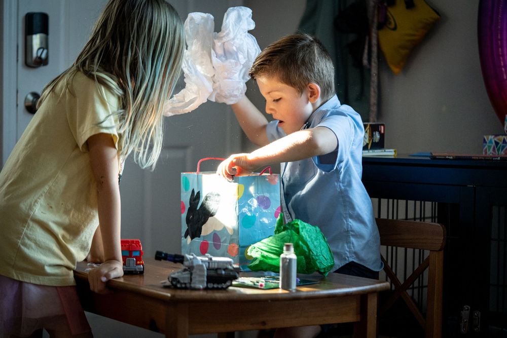 Two children perform a fun science experiment with colorful liquids and vapor at a darkened table.