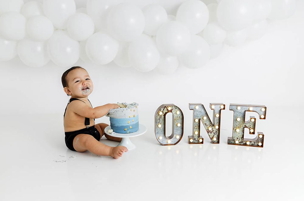 Winchester California cake smash photographer - Baby boy in black romper with cake and ONE marquee sign at 1st birthday cake smash session.
