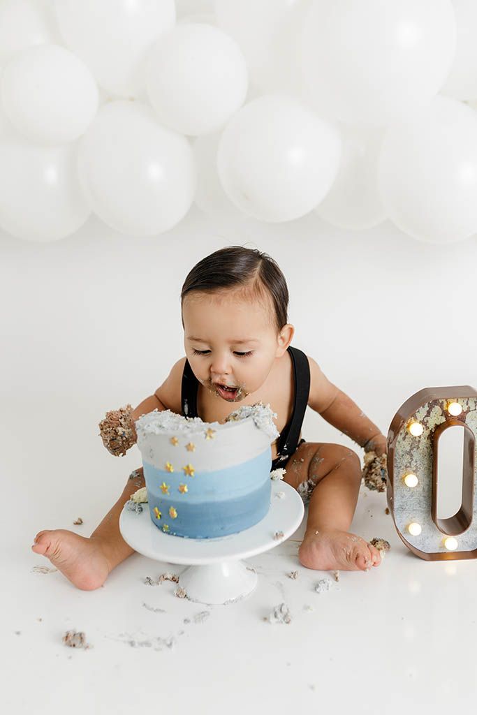 Adorable baby eating smash cake at neutral first birthday photoshoot in Winchester, CA.