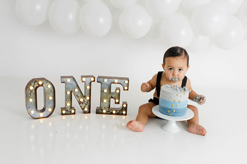Winchester CA cake smash photography - Baby's first birthday cake smash with ONE marquee letters against white balloon backdrop.