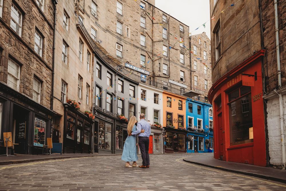 A steep cobblestone street lined with historic stone buildings in Edinburgh's Old Town.
