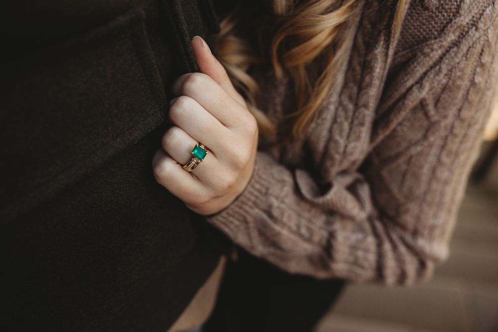 A person wearing a cozy brown knit sweater holds their hand up to show a turquoise ring.