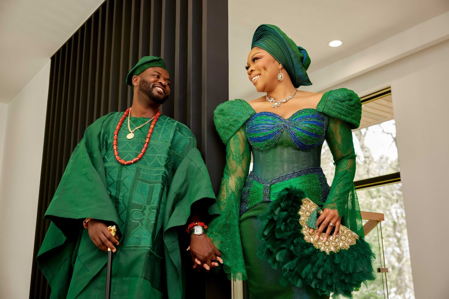 Couple in matching green Nigerian traditional attire smiling and holding hands at a wedding ceremony.