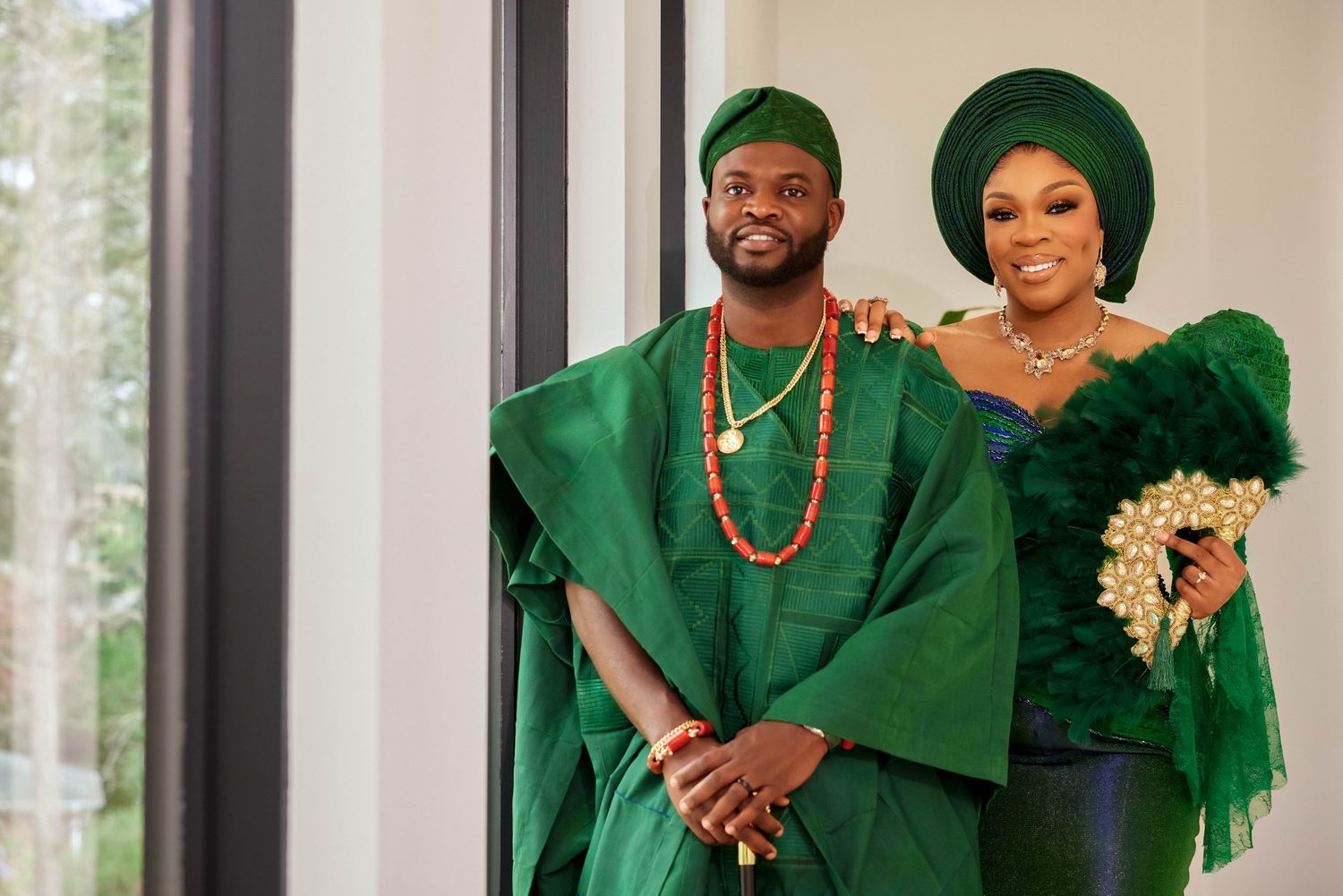 Nigerian couple in matching emerald green traditional attire smiling together at a wedding ceremony.