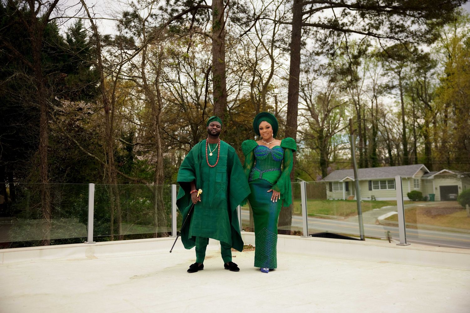 Nigerian couple in coordinating green traditional outfits standing together outdoors at a wedding.
