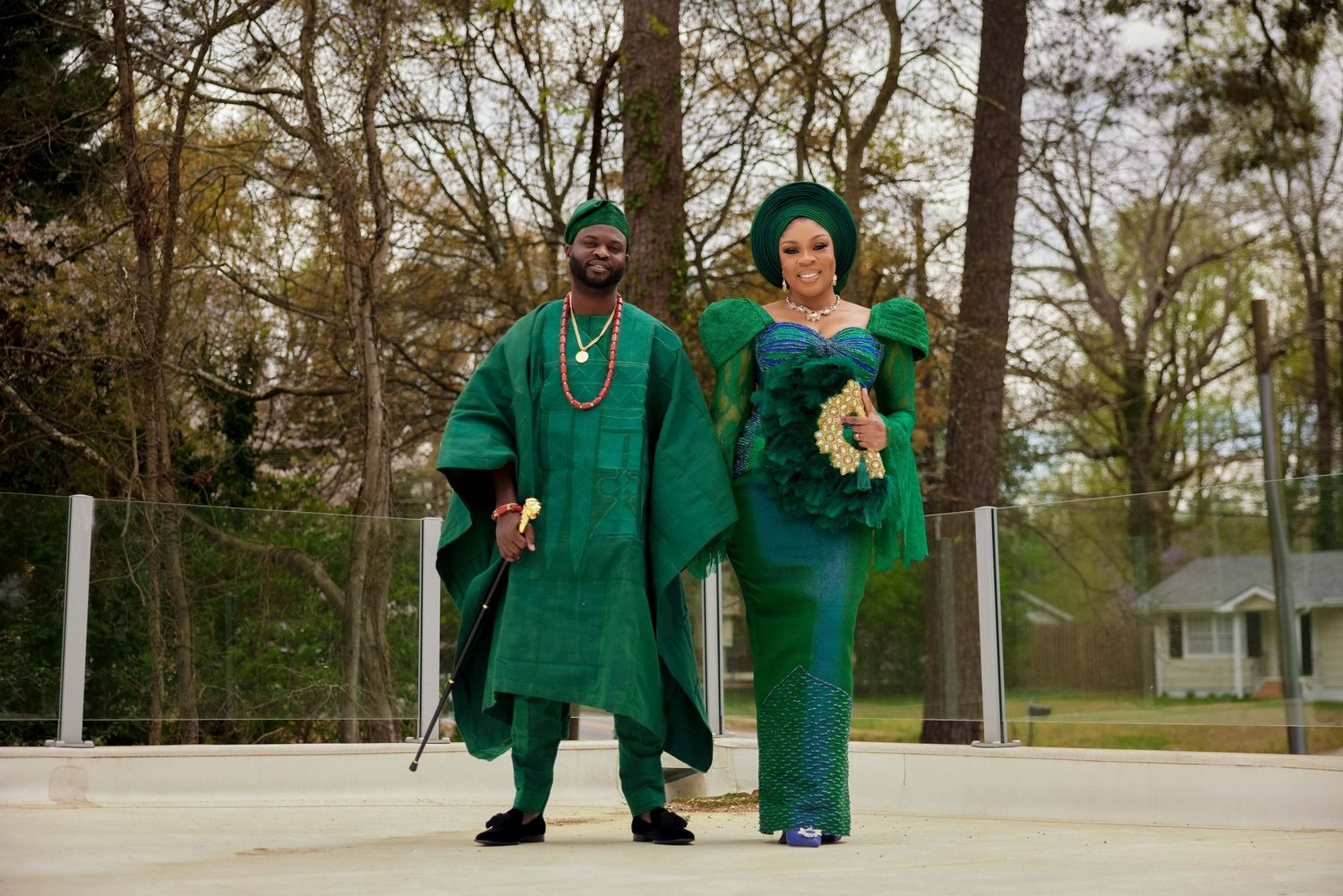 Couple in matching emerald green traditional Nigerian attire posing outdoors at a wedding celebration.