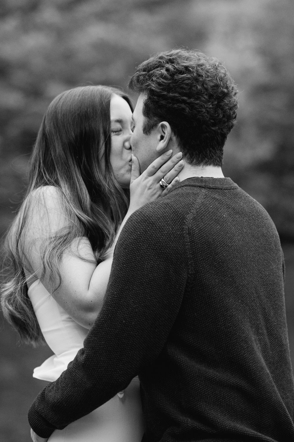Black and white photo of newly engaged couple sharing a kiss in Central Park.