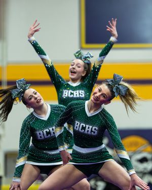 BCHS cheerleaders in green sparkle uniforms perform dynamic routine.