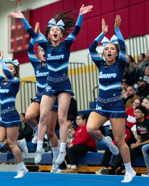 Lancers cheerleaders in blue sparkle uniforms jumping with arms raised at an indoor competition.