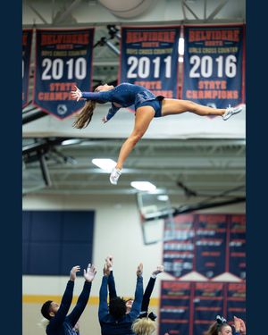 A cheerleader is tossed high into the air in a layout position by teammates during a cheer competition.