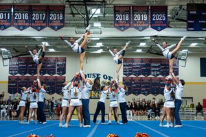 A cheerleading squad performs an impressive pyramid stunt formation during a competitive cheerleading meet.