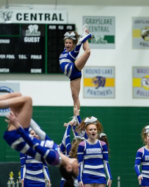Cheerleader elevated in stunt at Grayslake Central competition in blue and white uniform.