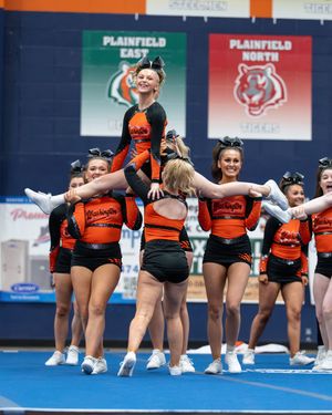 Cheerleaders in black and orange uniforms perform a stunt at Plainfield East and North competition.