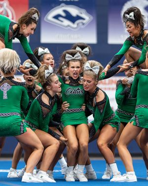 Green-uniformed Celtics cheerleading squad performs an intense floor routine at a competitive cheer event.