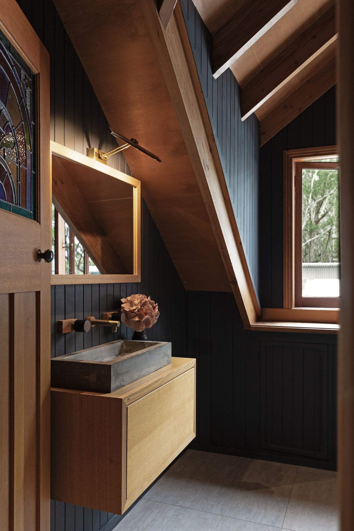 Moody bathroom interior photography with timber detailing and natural light in a South Coast coastal home.